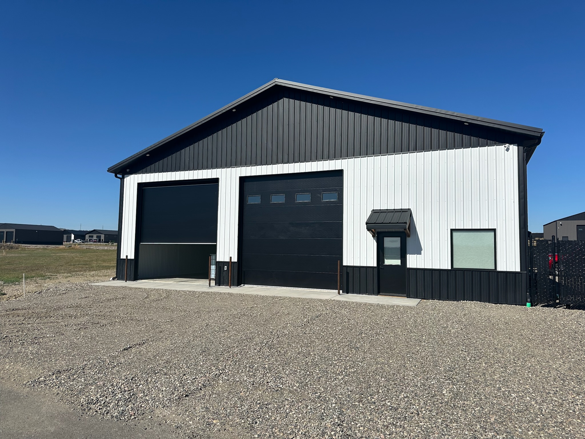 black and white shop two garage doors one man door and window