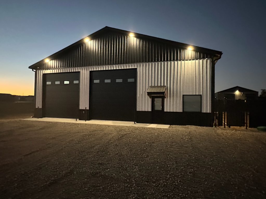 white and black shop with two doors man door and a window during the night